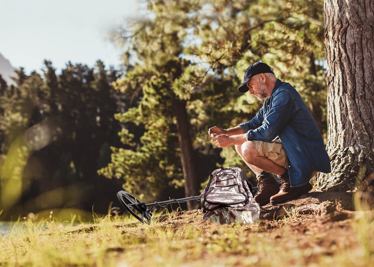 Nokta Legend with 12" x 9" LG30 Coil lifestyle pic of man looking at metal detecting finds