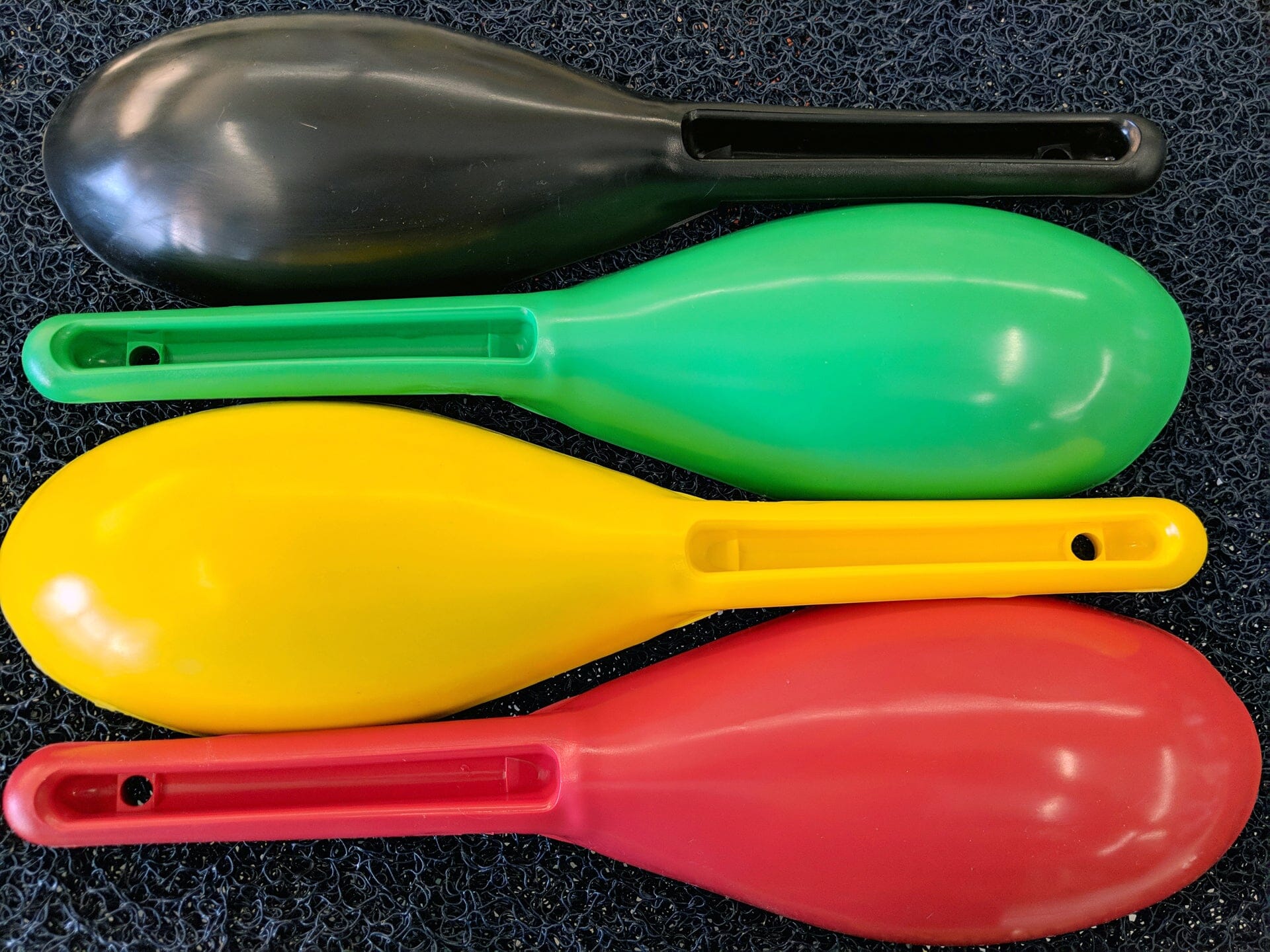 Bottom view of four gold nugget prospecting scoops, red, yellow, green, and black